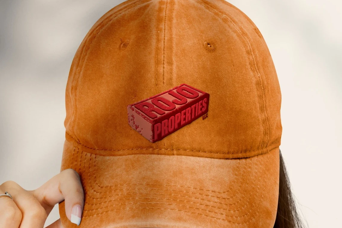 Washed orange dad cap with the Rojo Properties brick logo embroidered on the front panel