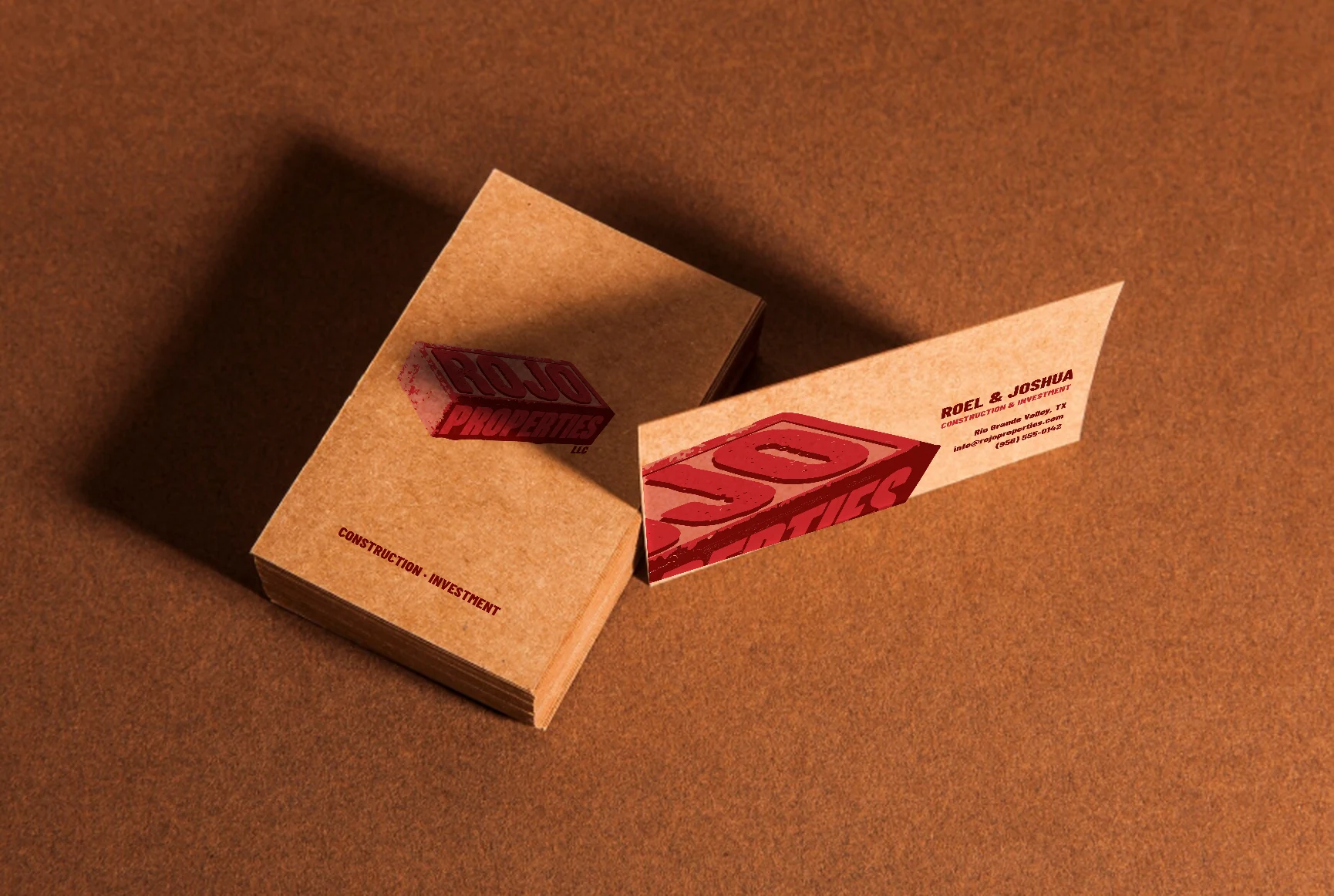 Kraft paper Rojo Properties business cards: a stack showing the brick logo and one card standing up showing the back