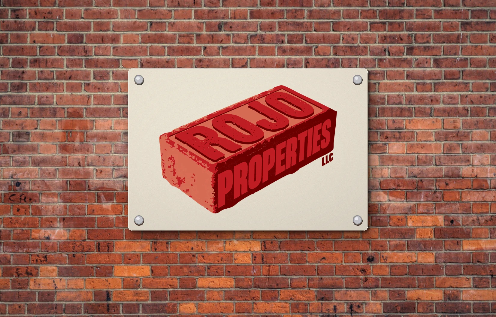 Rojo Properties brick logo on a plaque mounted to a red brick wall